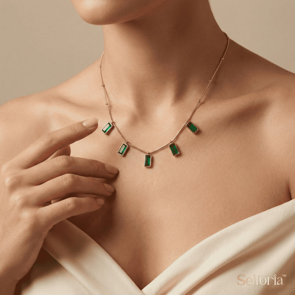 Close-up of emerald green drop necklace with gold finish, luxury statement jewelry for women