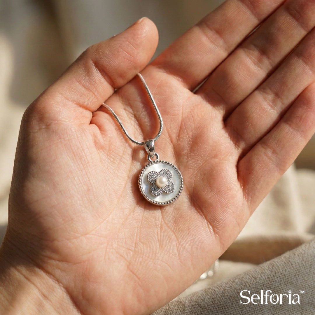Close-up of round silver pendant necklace featuring floral stone detailing and polished finish